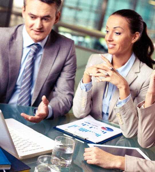 Portrait of business partners looking at laptop display at meeting, focus on pensive female